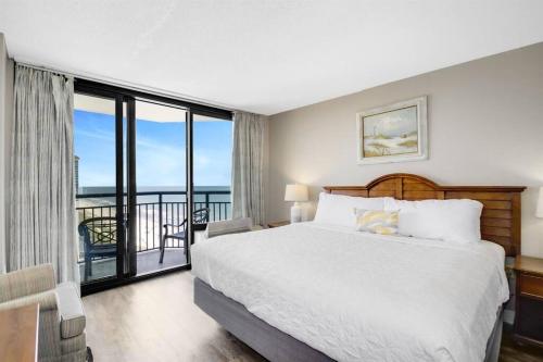 a bedroom with a large bed and a balcony at 1BR Oceanview Suite Relaxation Awaits Dogs OK! 1704 in Myrtle Beach