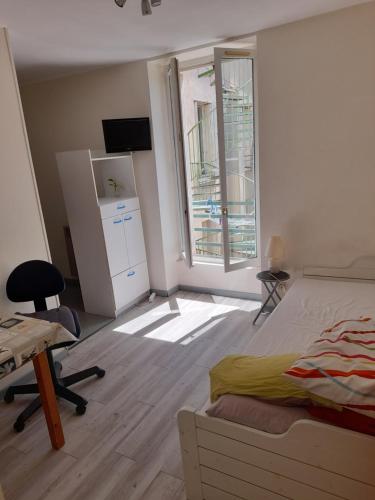 une chambre avec un lit, un bureau et une fenêtre dans l'établissement Super appartement centre ville Digne-les-Bains, à Digne-Les-Bains