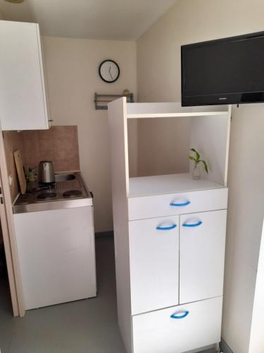 Elle comprend une petite cuisine avec une armoire blanche et une télévision. dans l'établissement Super appartement centre ville Digne-les-Bains, à Digne-Les-Bains