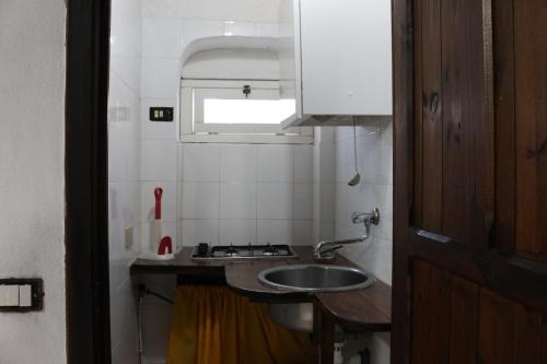 a small kitchen with a sink and a window at Abbamala Village in Bosa