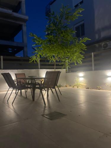 a table and chairs sitting next to a tree at Karamelas Vacation House in Nea Kalikratia