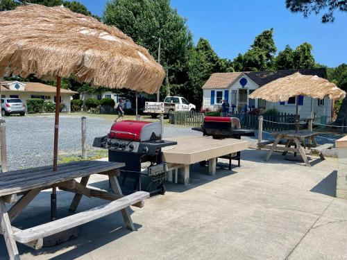 a group of picnic tables with a grill and straw umbrellas at The Maddox Inn in Chincoteague