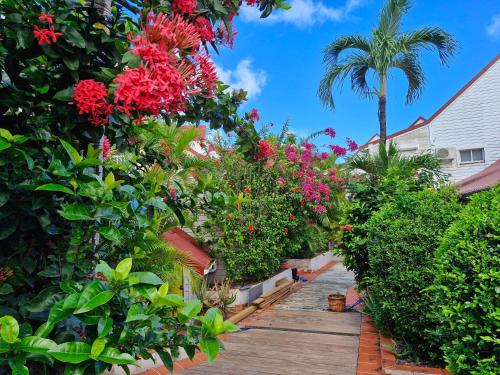 a garden with flowers and plants on a wooden walkway at Joli appartement entier sur jardin avec salle d'eau et chambre indépendantes et cuisine équipée in Marigot