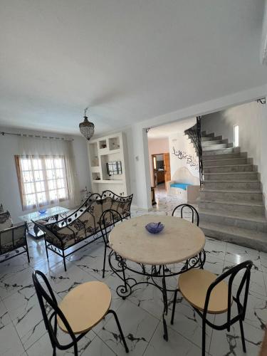 a living room with tables and chairs and stairs at Dar KM in Erriadh