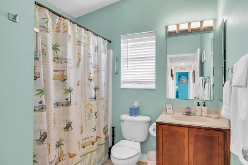 a bathroom with a shower curtain with a toilet and a sink at Blue Breeze in Duck Key