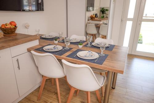 a kitchen with a wooden table and white chairs at APARTAMENT 15B BLUE MARINE Poddąbie Basen Odkryty Brodziki Plac Zabaw in Poddąbie