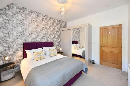 a bedroom with a large bed with a purple headboard at 20 The Courtyard, Ballochmyle House in Mauchline