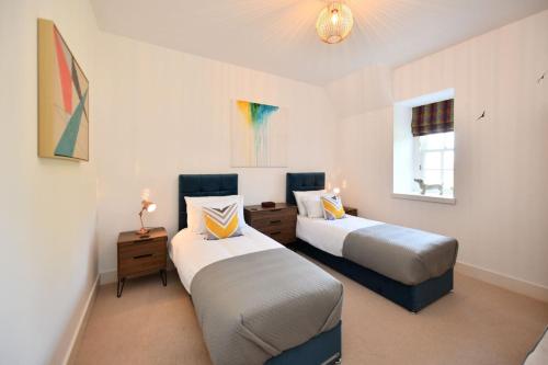 a bedroom with two beds and a window at 20 The Courtyard, Ballochmyle House in Mauchline