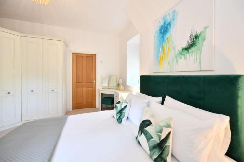 a bedroom with a white bed with a green headboard at 20 The Courtyard, Ballochmyle House in Mauchline