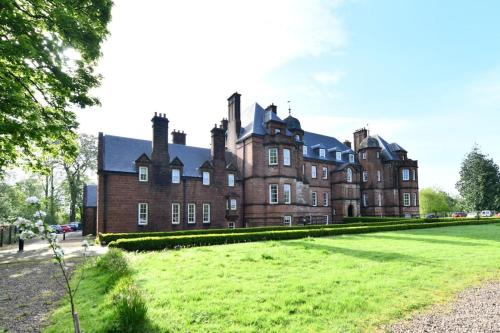 an old castle with a grassy field in front of it at 20 The Courtyard, Ballochmyle House in Mauchline