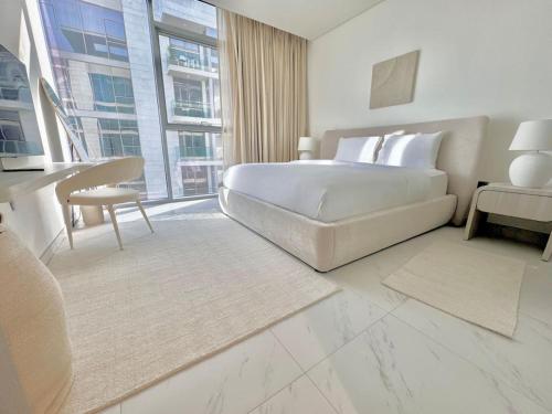 a white bedroom with a bed and a large window at Vacationer Holiday Homes I Waterfront 1 Bedroom I Stunning Lagoon View I District One in Dubai