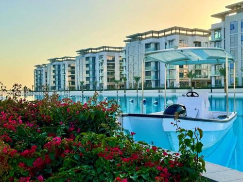 a boat in the water with buildings in the background at Vacationer Holiday Homes I Waterfront 1 Bedroom I Stunning Lagoon View I District One in Dubai