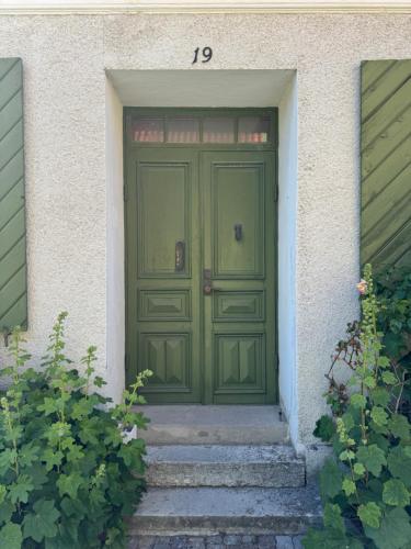 a green door of a house with stairs in front at Björnnästet med havsutsikt innanför murarna in Visby