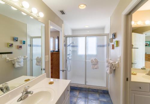 a white bathroom with a shower and a sink at Manatee Bay in Key Colony Beach