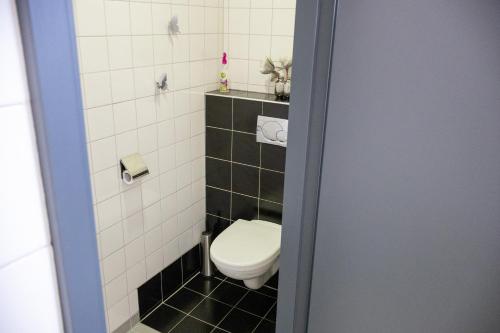 een badkamer met een toilet in zwart-witte tegels bij Voormalige Gevangenis Cel bij B&B Gezond aan Zee - Toegang Wellnesstuin meerprijs in Ouddorp