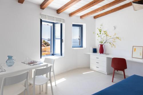 a white dining room with a white table and chairs at Captain Hook in Hydra
