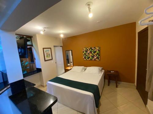 a bedroom with a bed and a painting on the wall at Pousada Sol e Cia Tur in Caraguatatuba