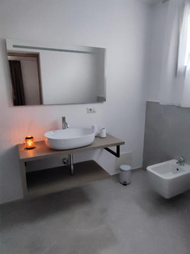 a bathroom with a sink and a mirror and a toilet at RIZZO RELAX Residence SALENTO in Capilungo