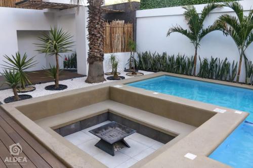 a swimming pool in the middle of a backyard with palm trees at ALDEA Luxury villas & suites in San Martín de las Pirámides