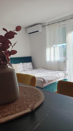 a room with a bed and a table with a plant at Apartman Lollita in Banja Luka