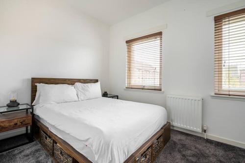 a white bedroom with a bed and two windows at Bright, modern 2 bedroom house with free parking! in Edinburgh