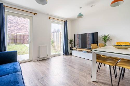 a living room with a table and chairs and a tv at Bright, modern 2 bedroom house with free parking! in Edinburgh