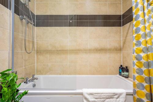 a bathroom with a white tub and a shower at Bright, modern 2 bedroom house with free parking! in Edinburgh