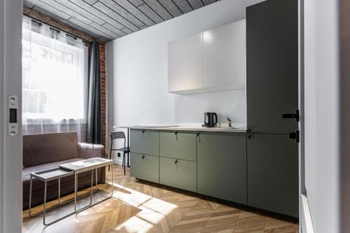 a kitchen with green cabinets and a couch at Old brick boutique apartments in Klaipėda