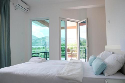 une chambre avec un grand lit blanc avec une grande fenêtre dans l'établissement Apartment Trebinje, à Trebinje