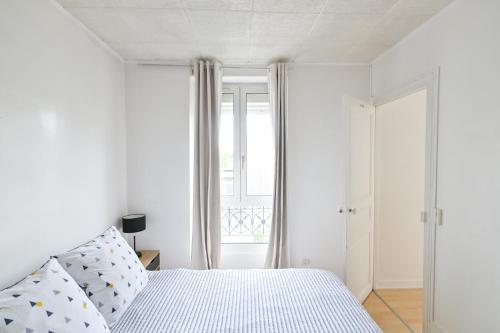 a white bedroom with a bed and a window at Appartement Cosy and Quiet Paris Villette in Le Pré-Saint-Gervais