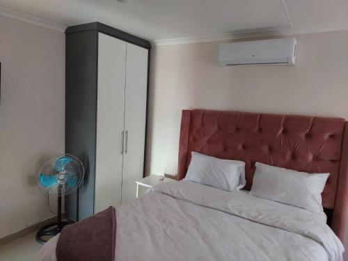 a bedroom with a bed with a red headboard and a fan at The Irenic Massage Spa and bnb in Hebron