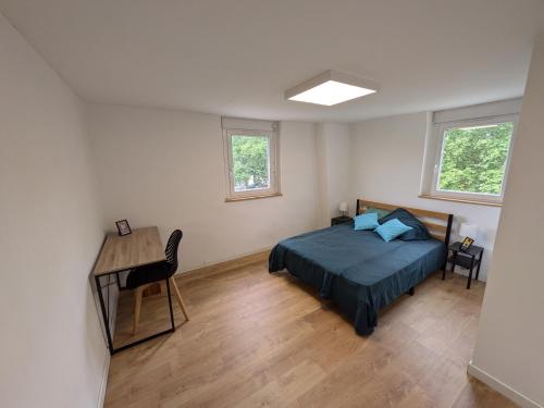 une chambre avec un lit et un bureau et deux fenêtres dans l'établissement Maison de ville Marmande, à Marmande