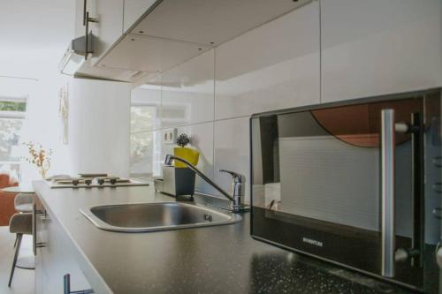 a kitchen with a sink and a microwave at Luxe Studiomuseumgebiedeftelinguvt in Tilburg