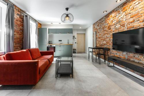a living room with a red couch and a brick wall at Old brick boutique apartments in Klaipėda