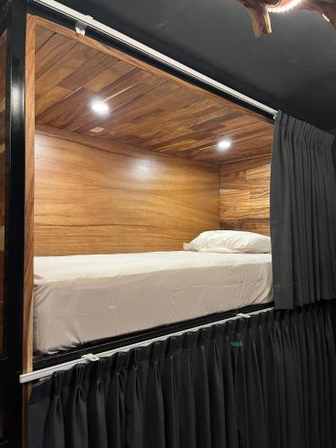 two beds in a room with a wooden wall at Homestal California Hostal en Tlaquepaque in Guadalajara