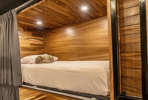 a bed in a room with a wooden wall at Homestal California Hostal en Tlaquepaque in Guadalajara