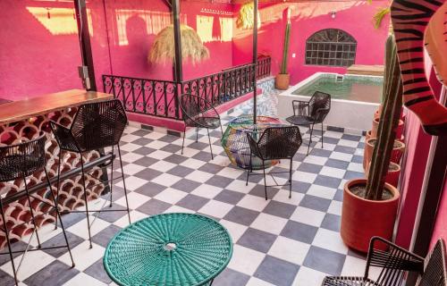 a pink room with a table and chairs and a pool at Homestal California Hostal en Tlaquepaque in Guadalajara
