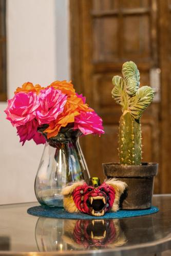 a table with two vases with flowers and a cactus at Homestal California Hostal en Tlaquepaque in Guadalajara
