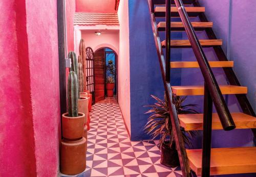 a hallway with a staircase and blue and pink walls at Homestal California Hostal en Tlaquepaque in Guadalajara