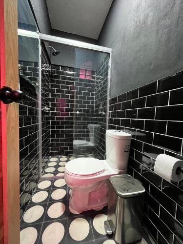 a bathroom with a pink toilet and black tiles at Homestal California Hostal en Tlaquepaque in Guadalajara