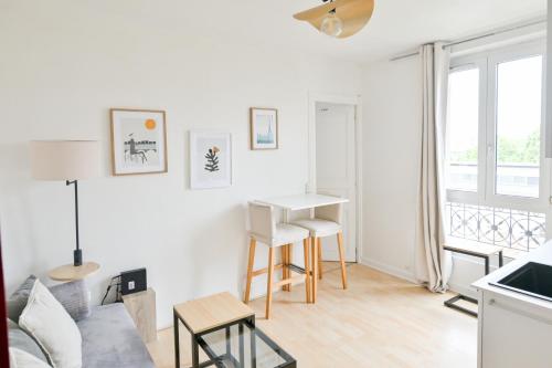 a white living room with a table and a couch at Appartement Cosy and Quiet Paris Villette in Le Pré-Saint-Gervais