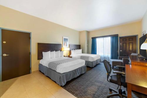 a hotel room with two beds and a desk at Best Western Naples Plaza Hotel in Naples