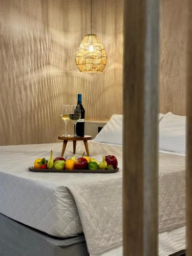 a tray of fruit and a bottle of wine on a bed at Psamathi Living & Taste in Marathi