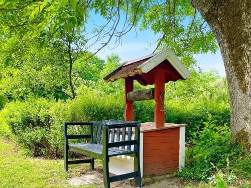 a bird feeder with a bench next to a tree at 4 person holiday home in FÄRJESTADEN-By Traum in Färjestaden