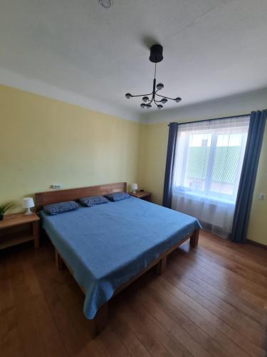 a bedroom with a blue bed and a window at Pie Parka in Alūksne