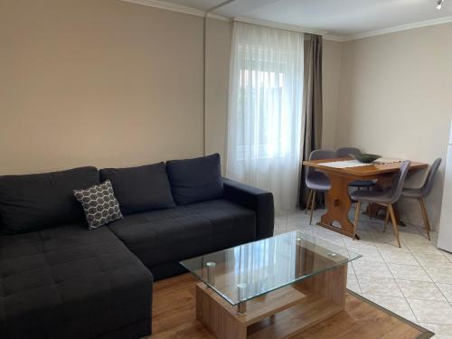 a living room with a black couch and a table at Margaret Apartment in Balatonkeresztúr