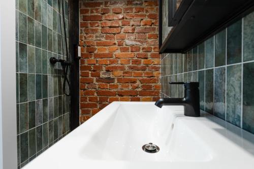 a bathroom with a sink and a brick wall at Old brick boutique apartments in Klaipėda