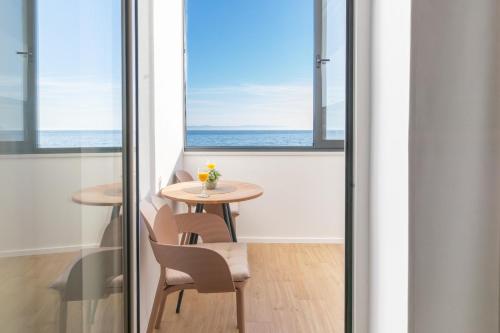 a table and chairs in a room with a view of the ocean at Apartments Malina in Tučepi