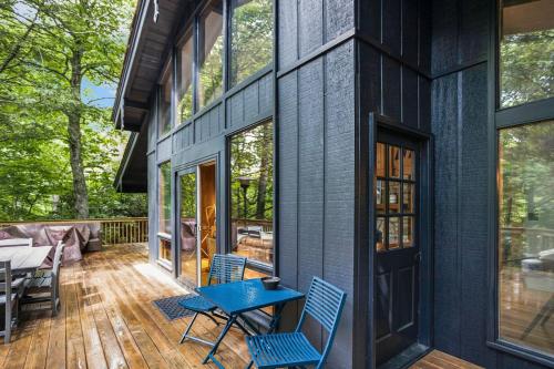a black house with a blue table and chairs on a deck at Alpine Sanctuary in Valle Crucis