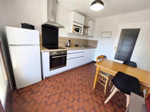 Il comprend une cuisine équipée d'une table, d'un réfrigérateur, d'une table et de chaises. dans l'établissement Résidence Le Choiseul - Agréable logement au coeur de la ville ! MAE-7961, à Aix-les-Bains